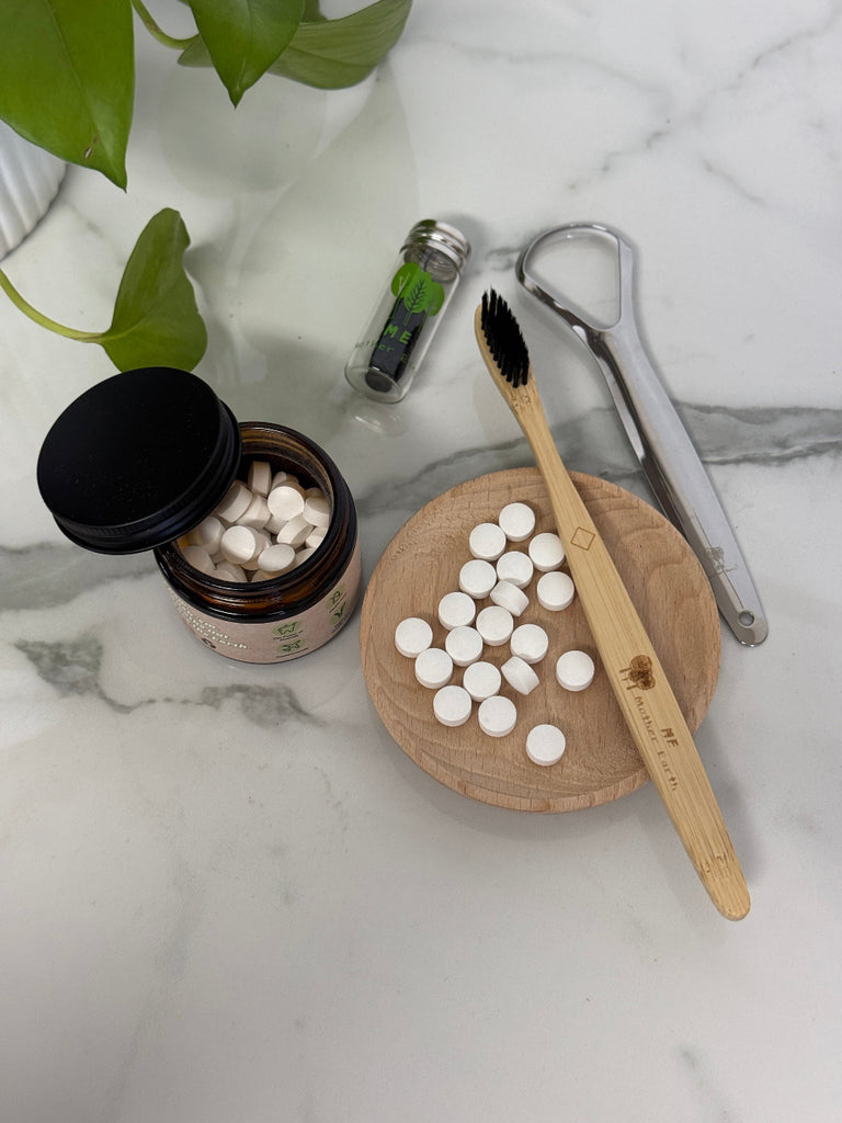 Jar of tablets, bamboo toothbrush, and other items on a marble surface