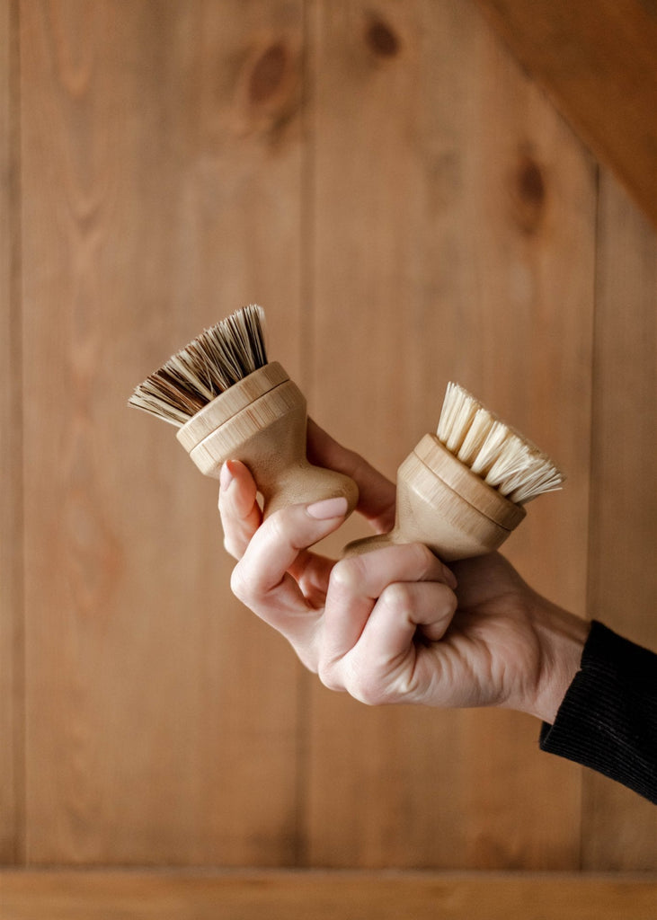 Hand holding two wooden brushes against a wooden background
